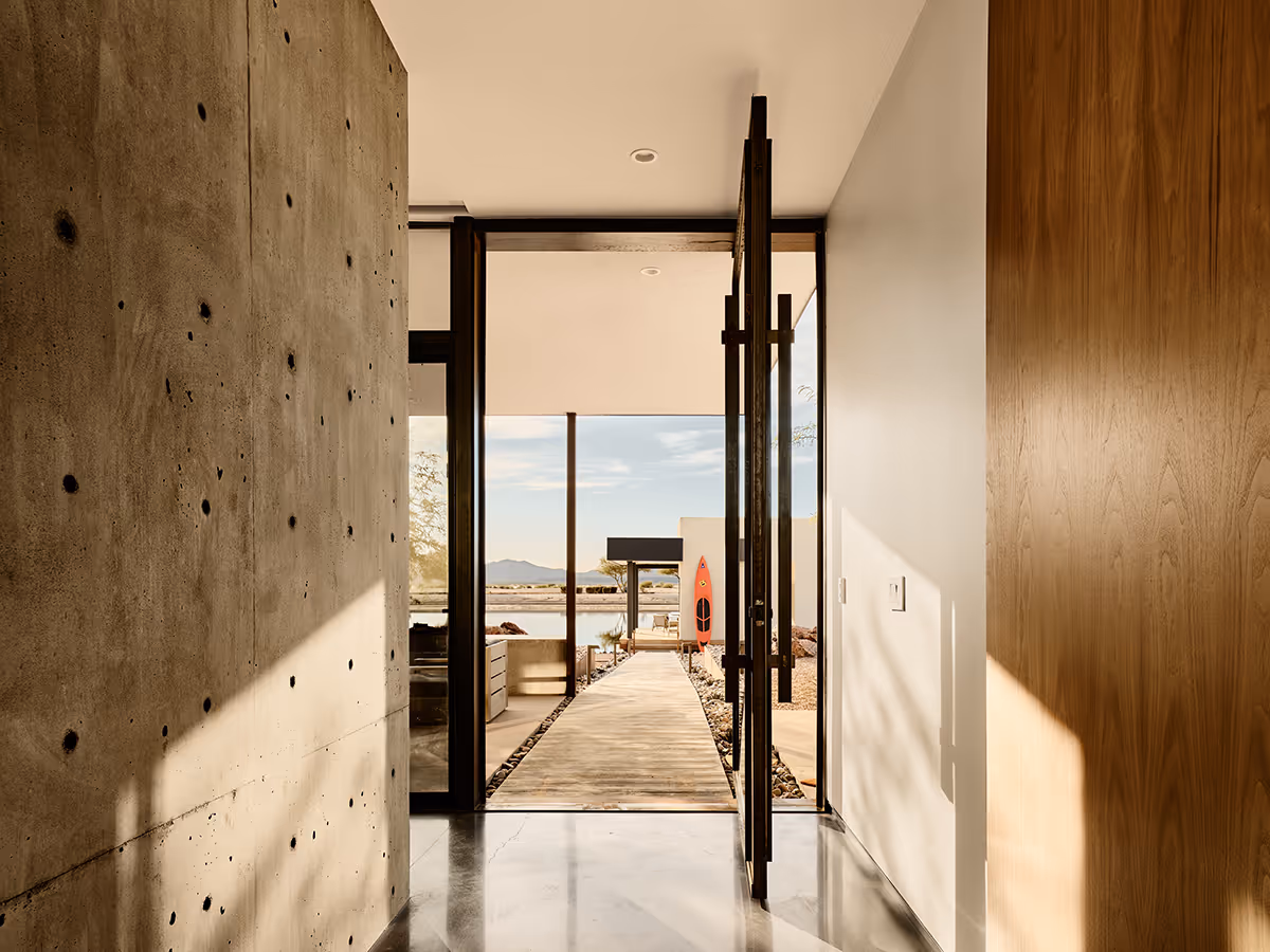 steel and glass pivot door in entry with cast in place concrete wall at a desert modern house in Arizona by The Ranch Mine