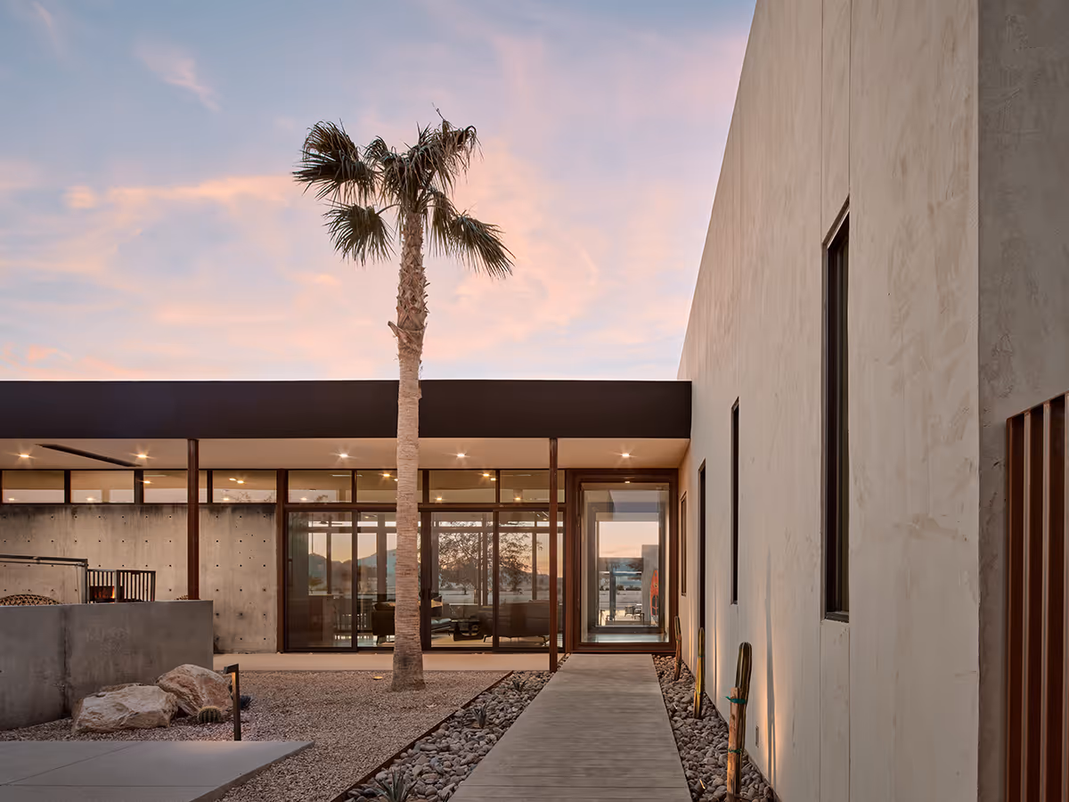 dusk view entry courtyard with a palm tree at a desert modern house in Arizona by The Ranch Mine