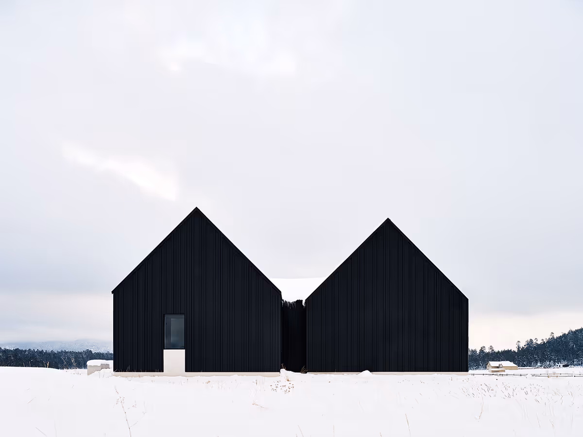 Modern Scandinavian black exterior house with gabled roofs in Flagstaff, Arizona by The Ranch Mine in the snow
