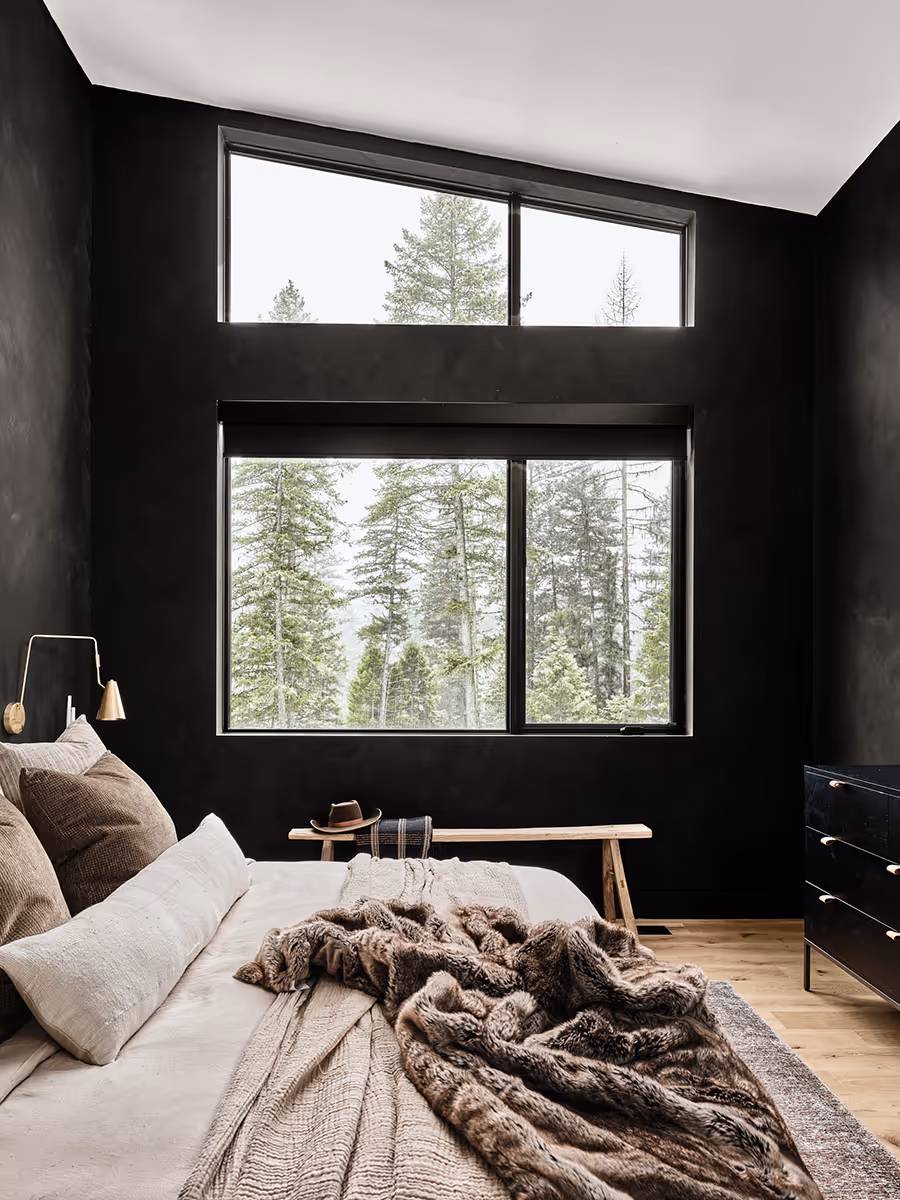 Black cozy bedroom looking at a pine forest in Whitefish, Montana