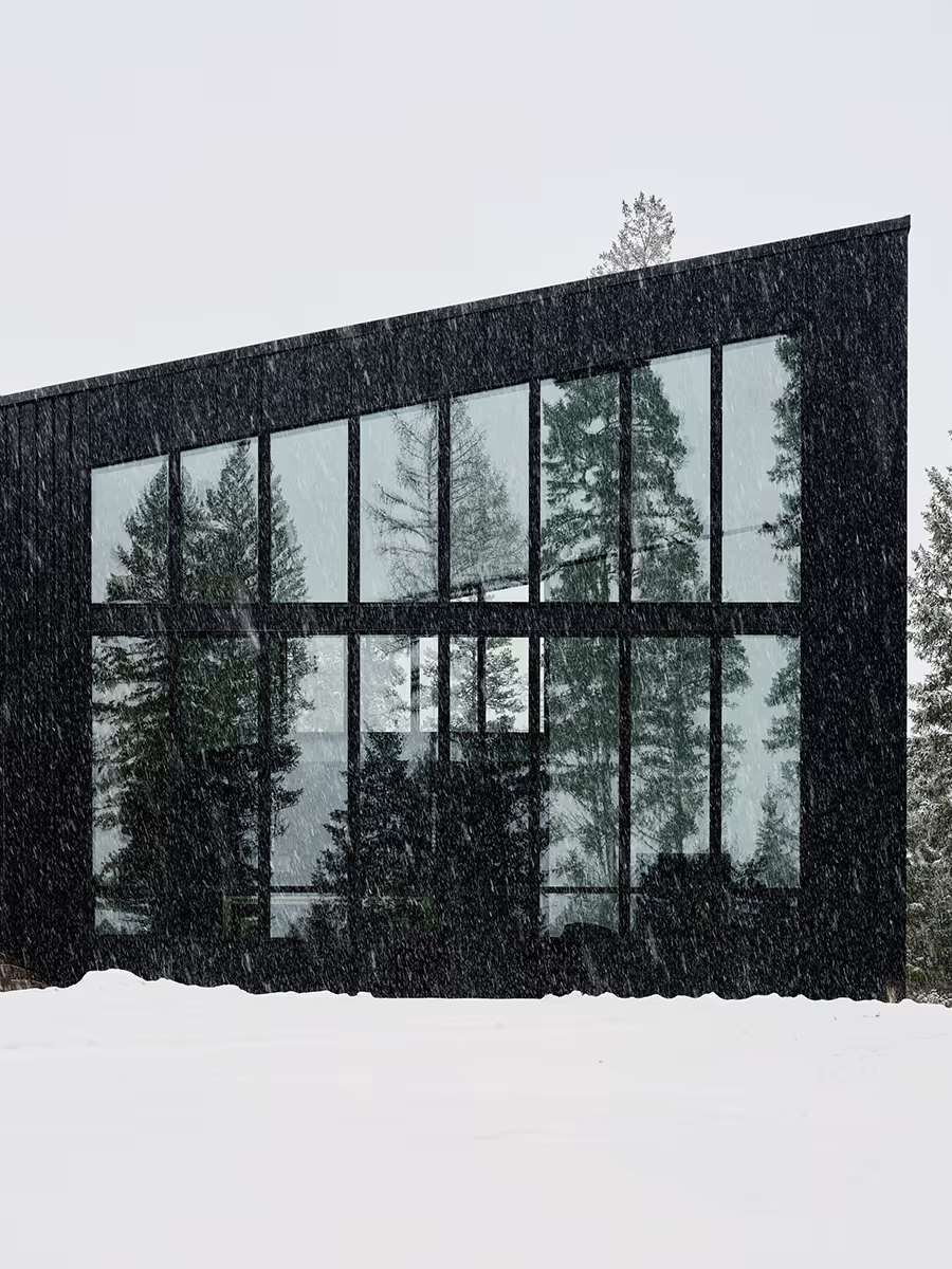black modern mountain house with wall of glass windows in Whitefish, Montana