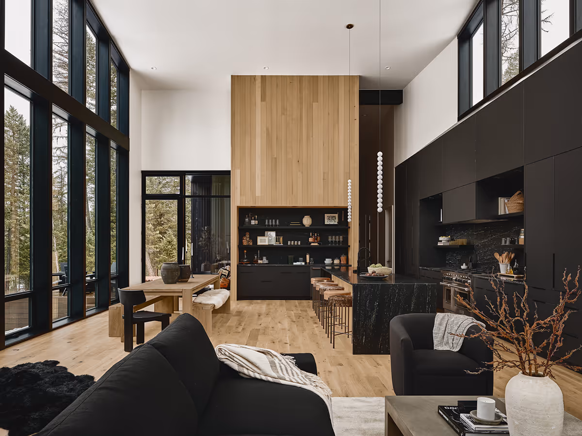 Great room with a wood bar and lots of windows looking at a pine forest in Whitefish, Montana