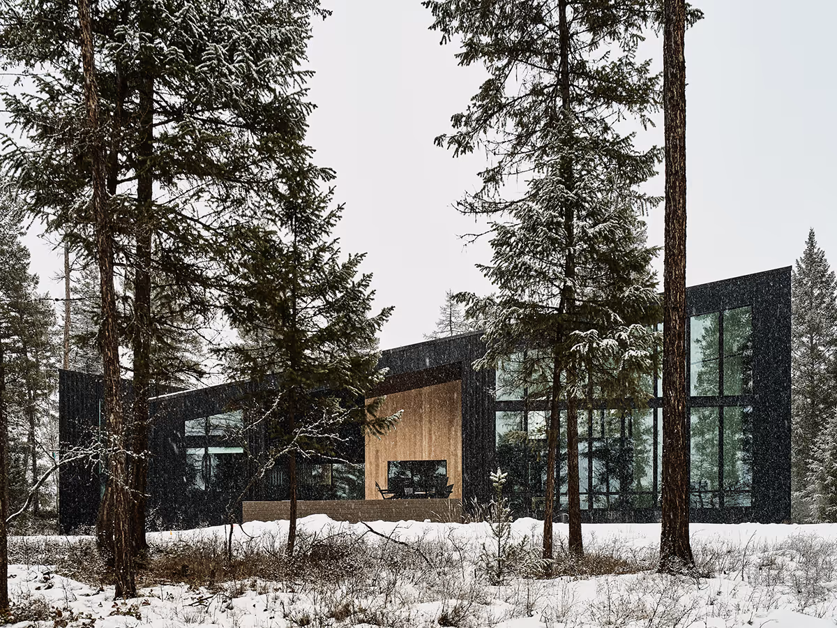black modern mountain house in a pine forest in Whitefish, Montana