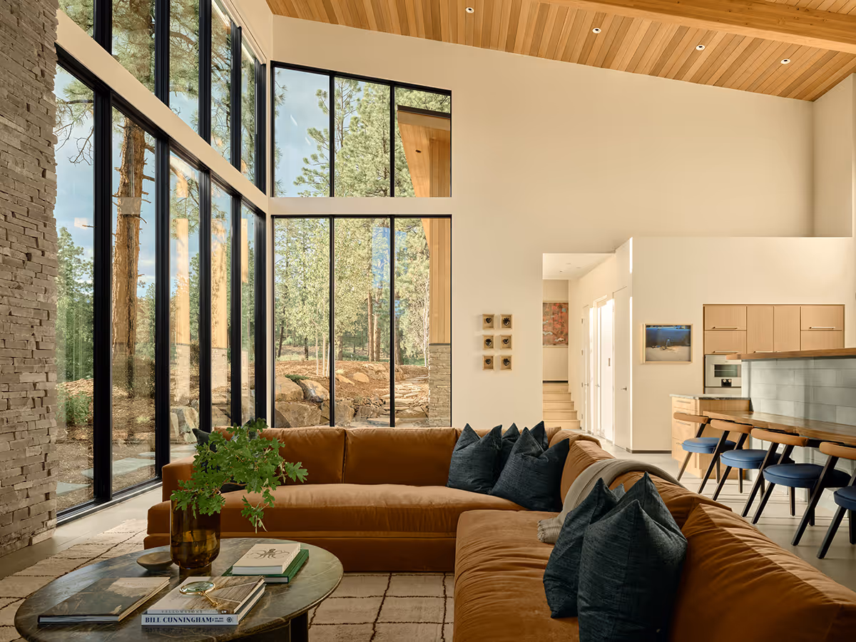 interior of modern mountain home in Durango, Colorado with lots of glass, a stacked stone chimney and wood ceiling by The Ranch Mine
