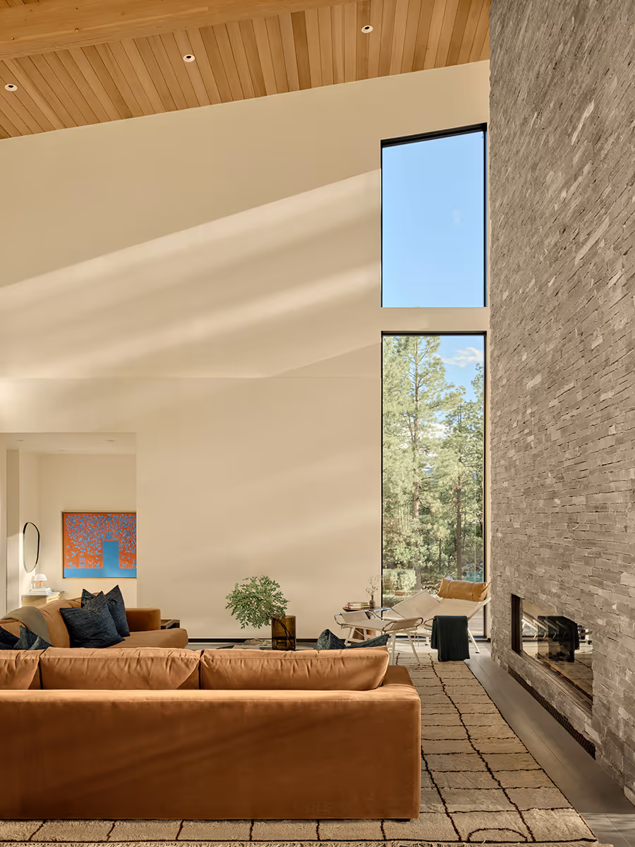interior of modern mountain home in Durango, Colorado with lots of glass, a stacked stone chimney and wood ceiling by The Ranch Mine