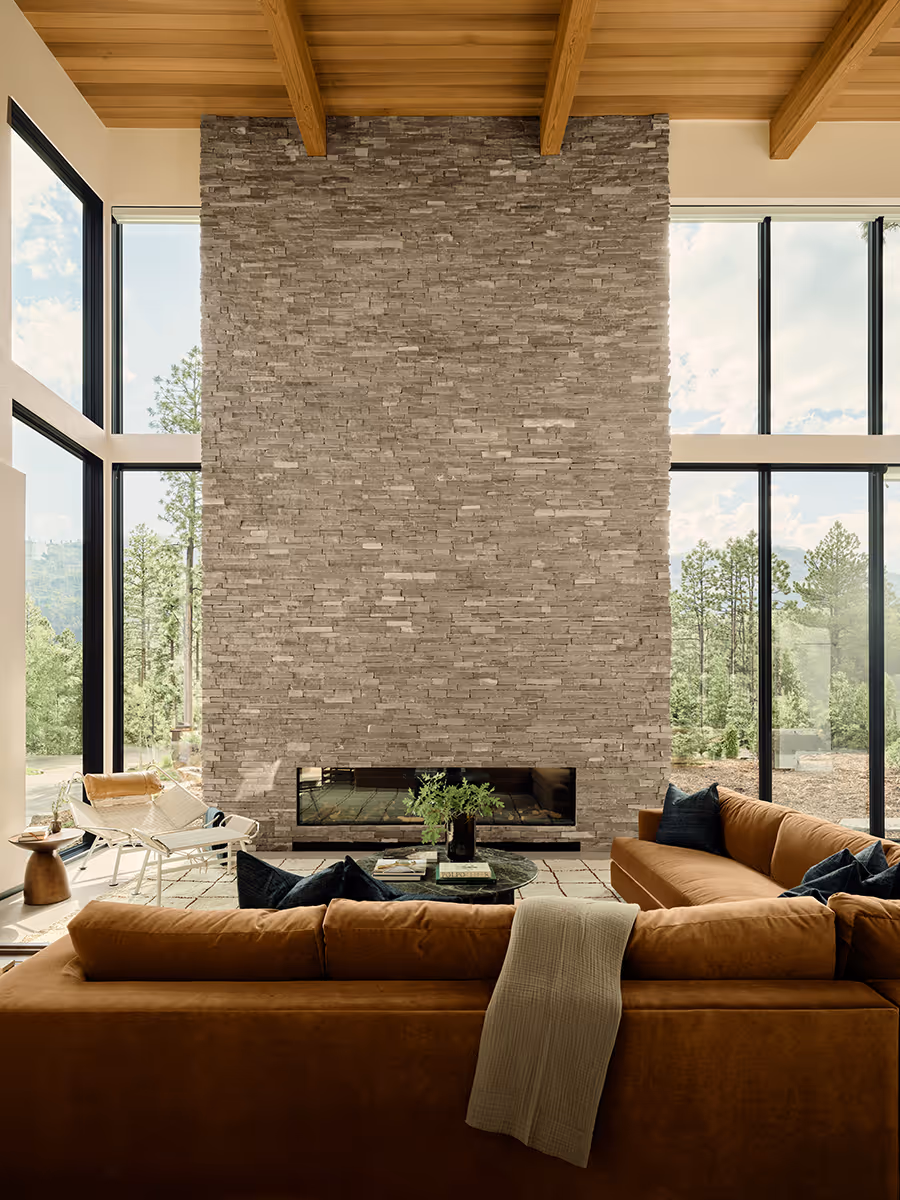 interior of modern mountain home in Durango, Colorado with lots of glass, a stacked stone chimney and wood ceiling by The Ranch Mine