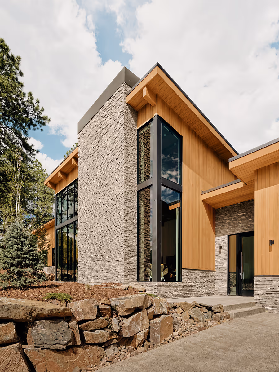 modern mountain home in Durango, Colorado with lots of glass, a stacked stone chimney and wood siding by The Ranch Mine