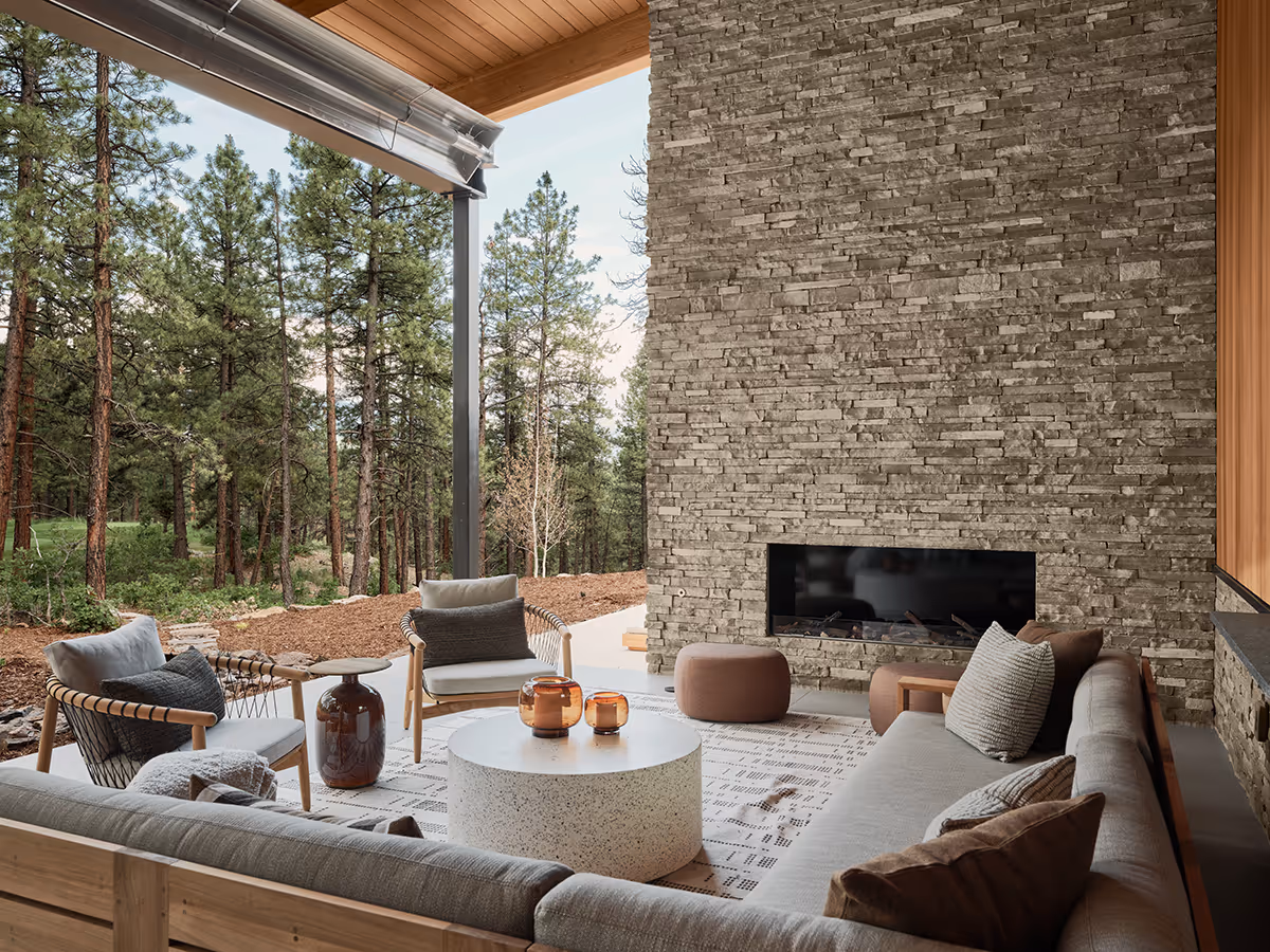 modern mountain home in Durango, Colorado with lots of glass, a stacked stone chimney and wood siding by The Ranch Mine