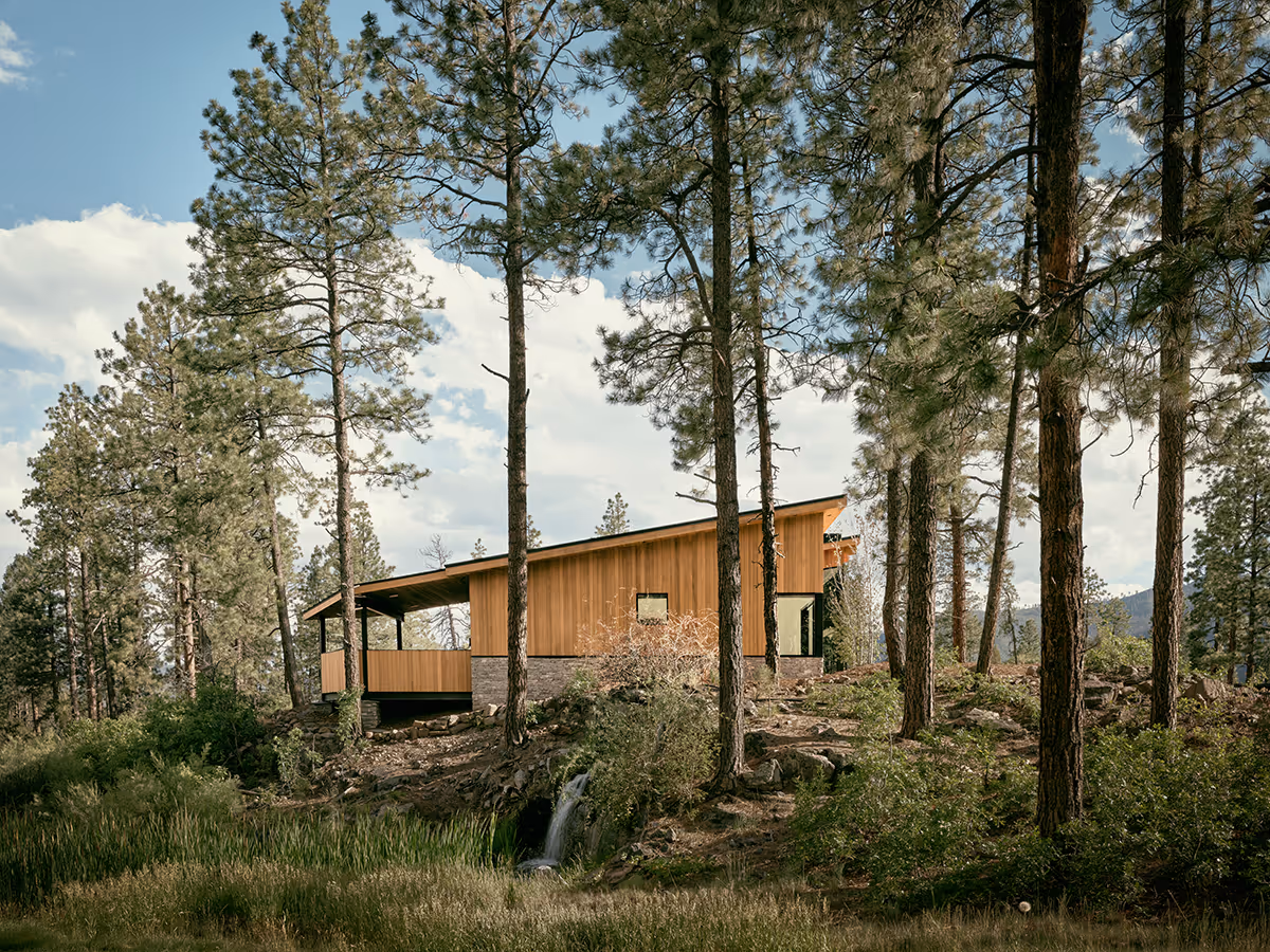 modern mountain home in Durango, Colorado with lots of glass, a stacked stone chimney and wood siding by The Ranch Mine