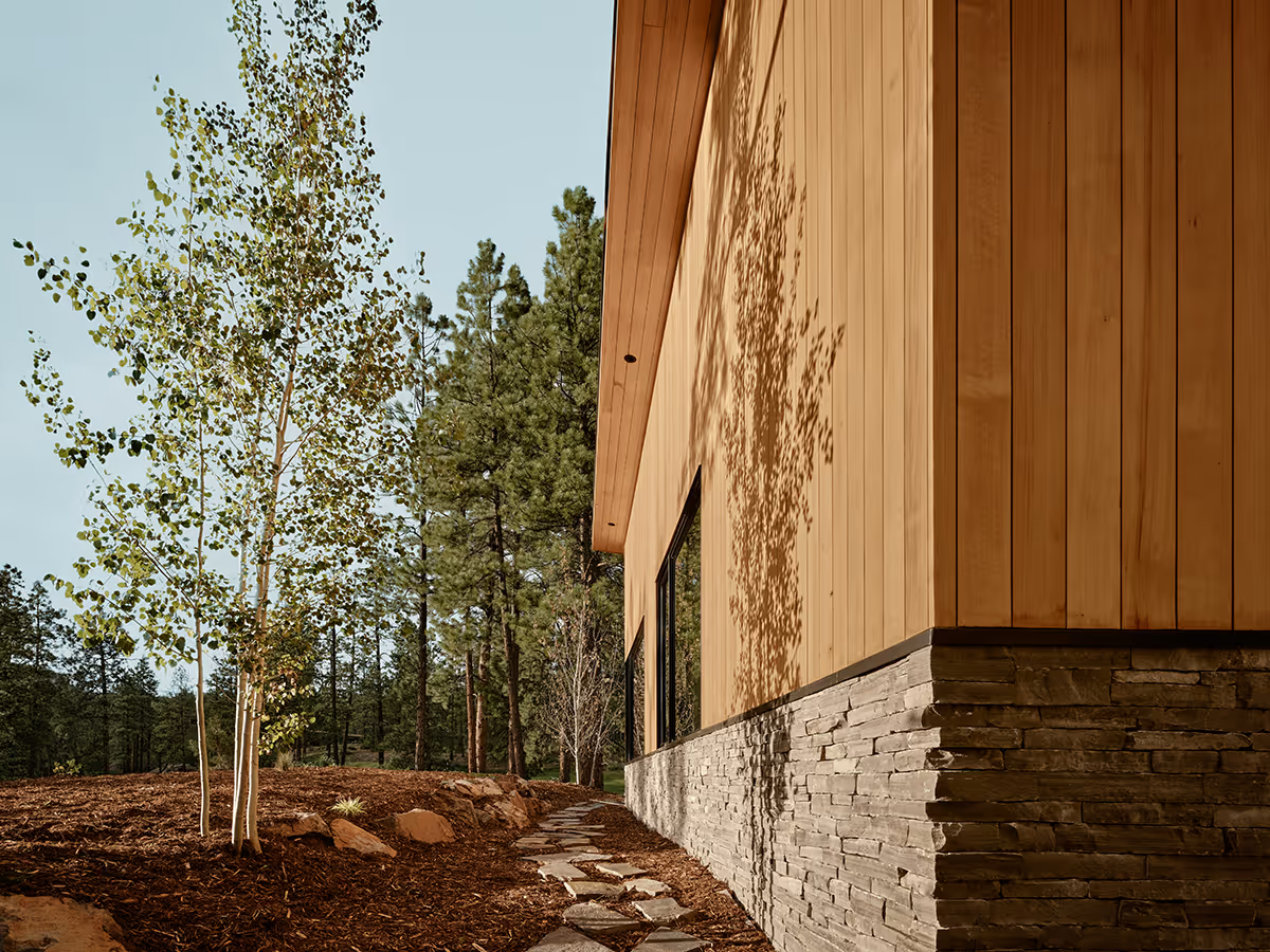 modern mountain home in Durango, Colorado with lots of glass, a stacked stone chimney and wood siding by The Ranch Mine