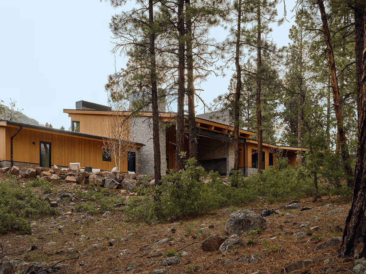 modern mountain home in Durango, Colorado with lots of glass, a stacked stone chimney and wood siding by The Ranch Mine