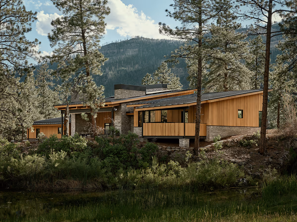 modern mountain home in Durango, Colorado with lots of glass, a stacked stone chimney and wood siding by The Ranch Mine