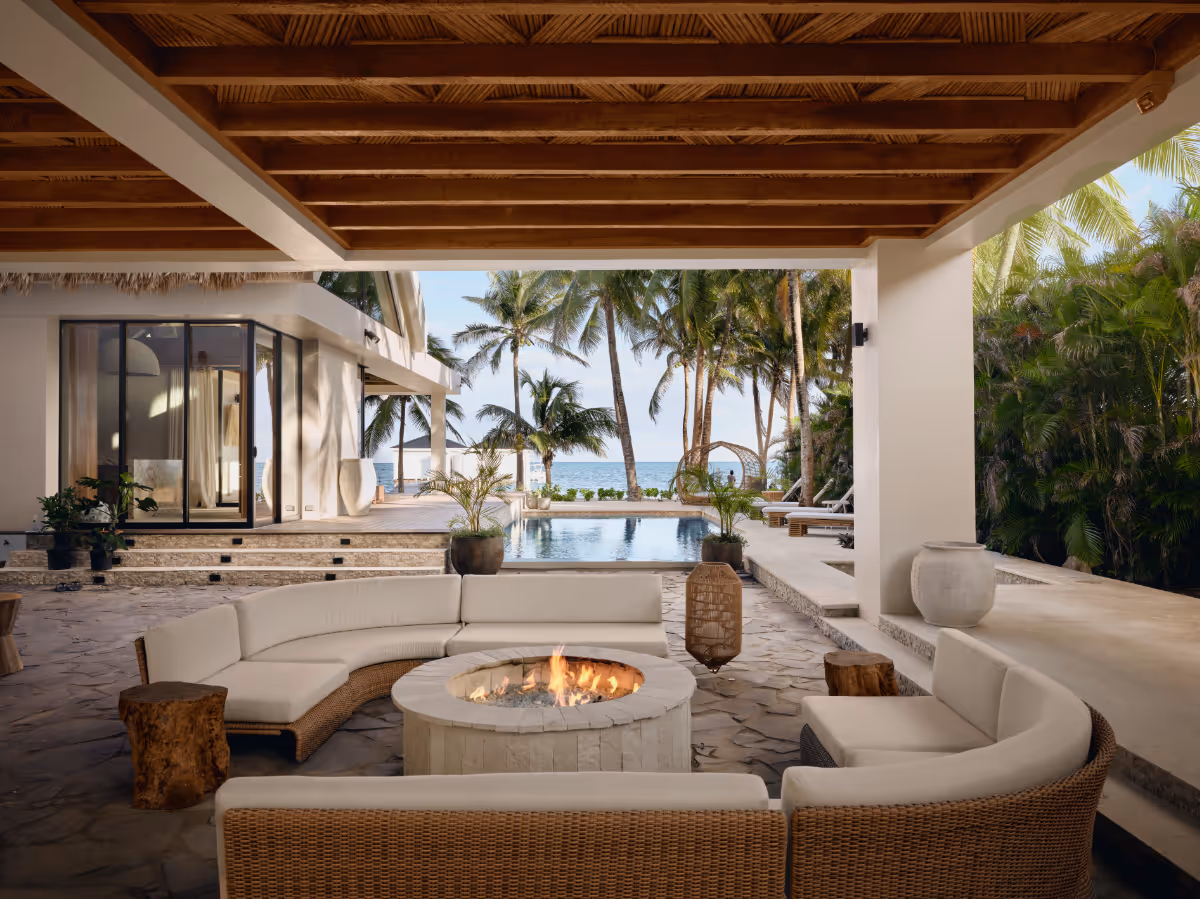 Covered patio with a fire pit overlooking a pool tropical modern house in Belize by The Ranch Mine