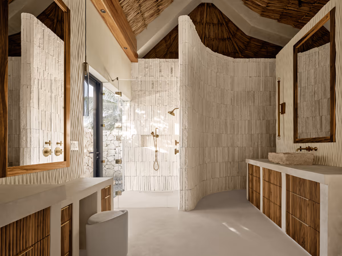 Concrete counter with wood cabinets and curved shower wall at a tropical modern house in Belize by The Ranch Mine