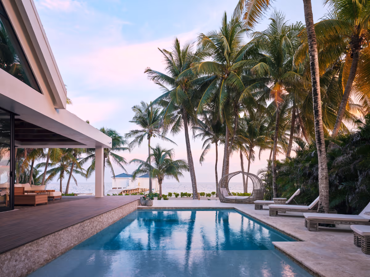 Pool overlooking the ocean and palm trees at a tropical modern house in Belize by The Ranch Mine