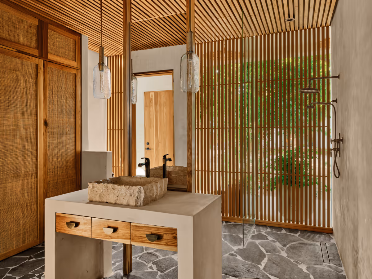 Pool bathroom with privacy slats and stone sink at a tropical modern house in Belize by The Ranch Mine