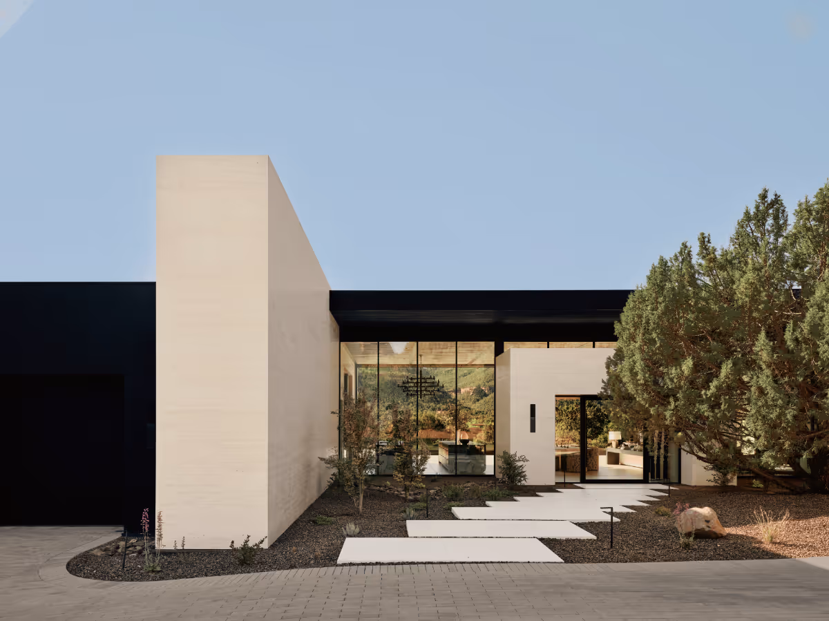Limestone and dark-stucco entry court with stepping pads and full-height glass to a modern new build home in Sedona by The Ranch Mine