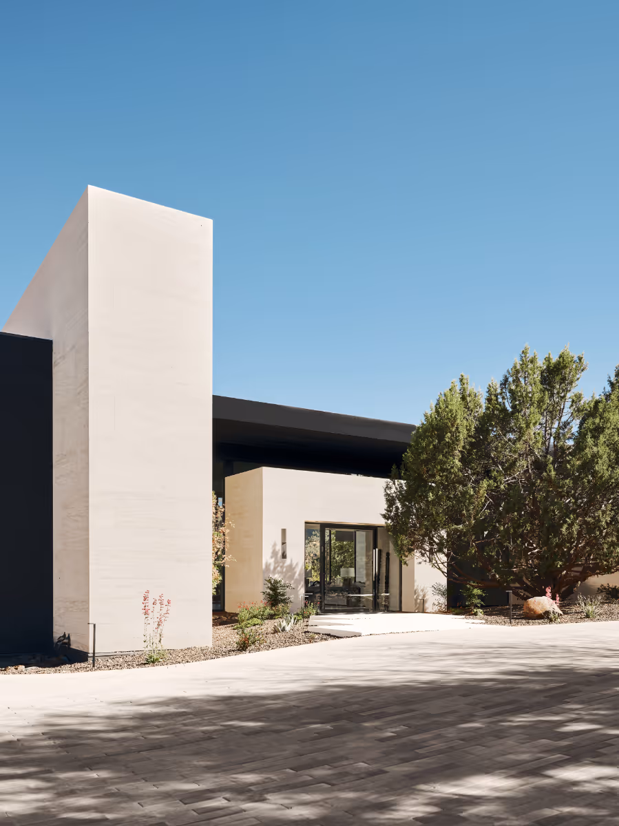 Limestone and dark-stucco entry court with stepping pads and full-height glass to a modern new build home in Sedona by The Ranch Mine