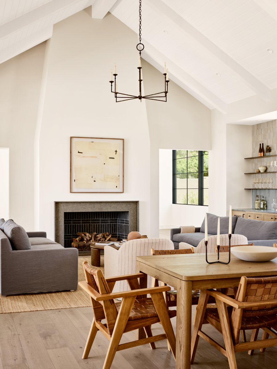Central fireplace anchoring a cozy living room with white wood beams on the ceiling by The Ranch Mine