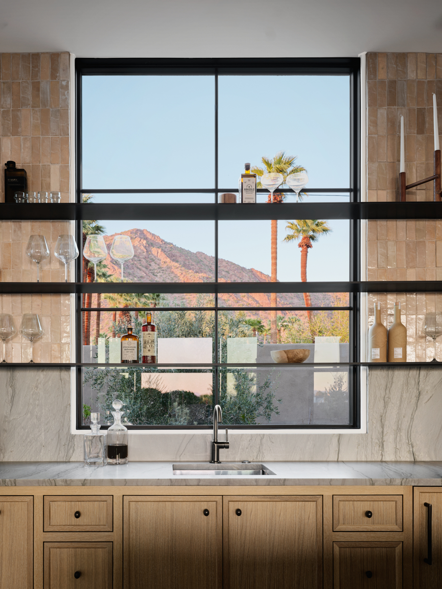 Floating steel shelves in front of window framing Camelback Mountain and palm trees by The Ranch Mine