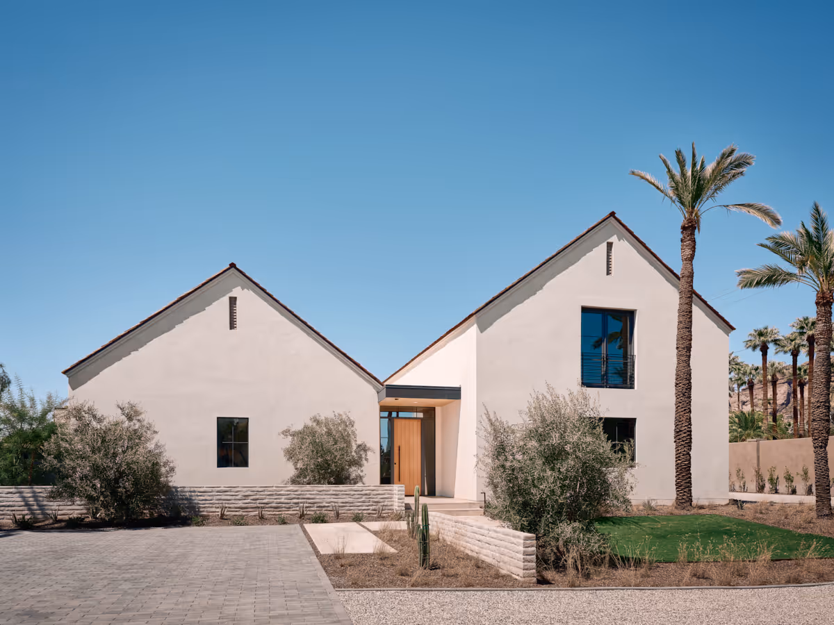 Entry court with precise stucco forms and desert planting leading toward the porch, by The Ranch Mine