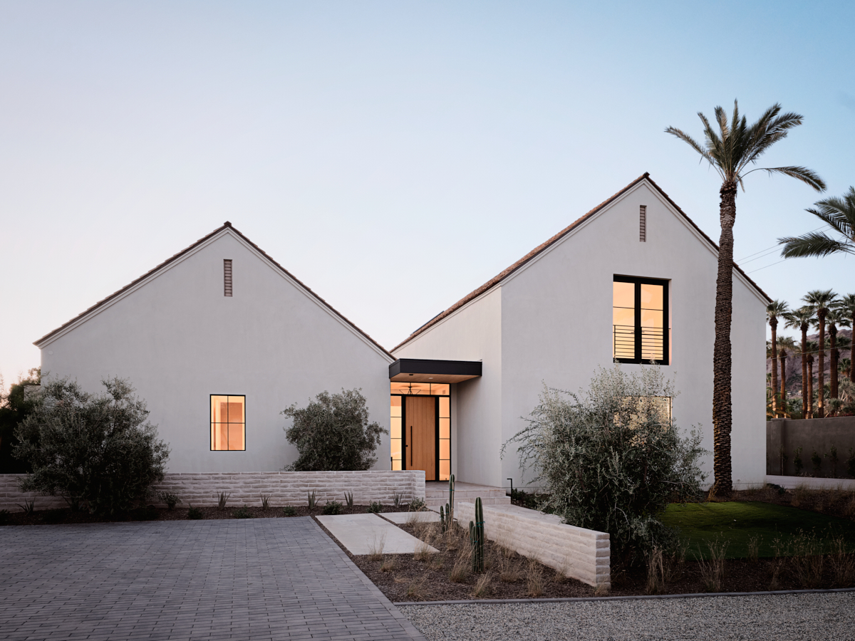 Twilight view of entry court with precise stucco forms and desert planting leading toward the porch, by The Ranch Mine