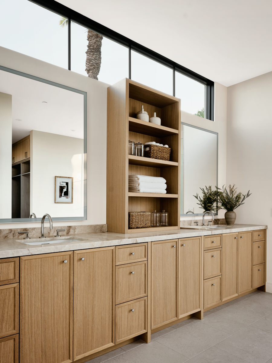 Primary bath with warm wood cabinets by The Ranch Mine