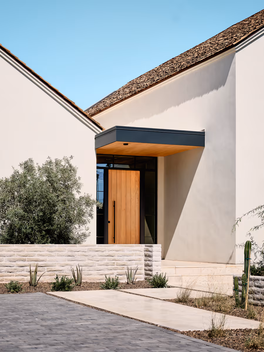 Entry court with precise stucco forms and desert planting leading toward the porch, by The Ranch Mine