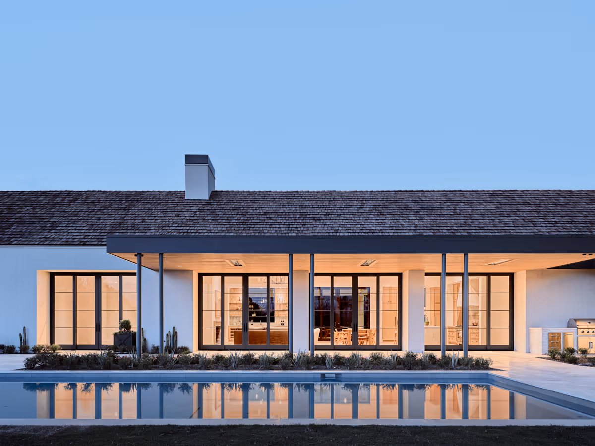 Twilight exterior, gable sequence and porch rhythm reflected in still water, by The Ranch Mine