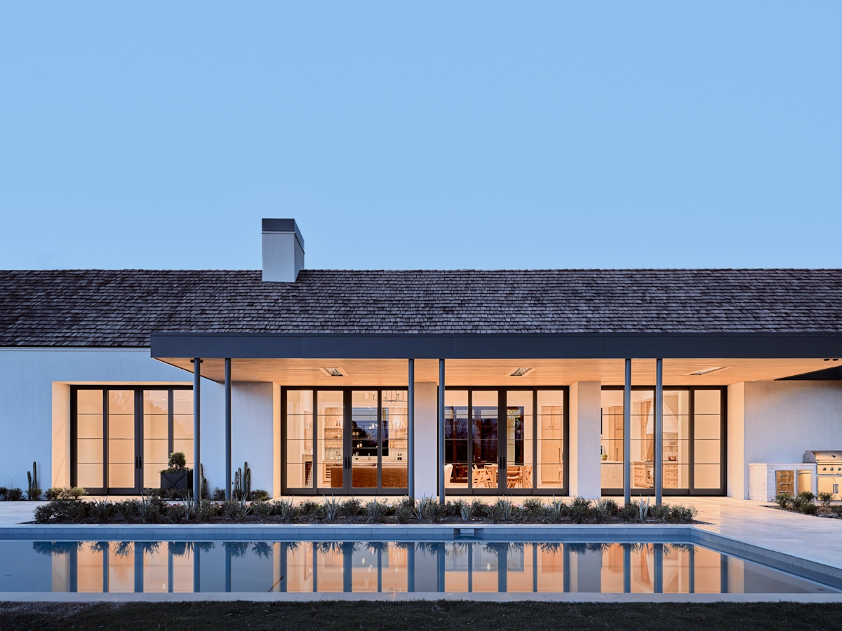 Twilight exterior, gable sequence and porch rhythm reflected in still water, by The Ranch Mine
