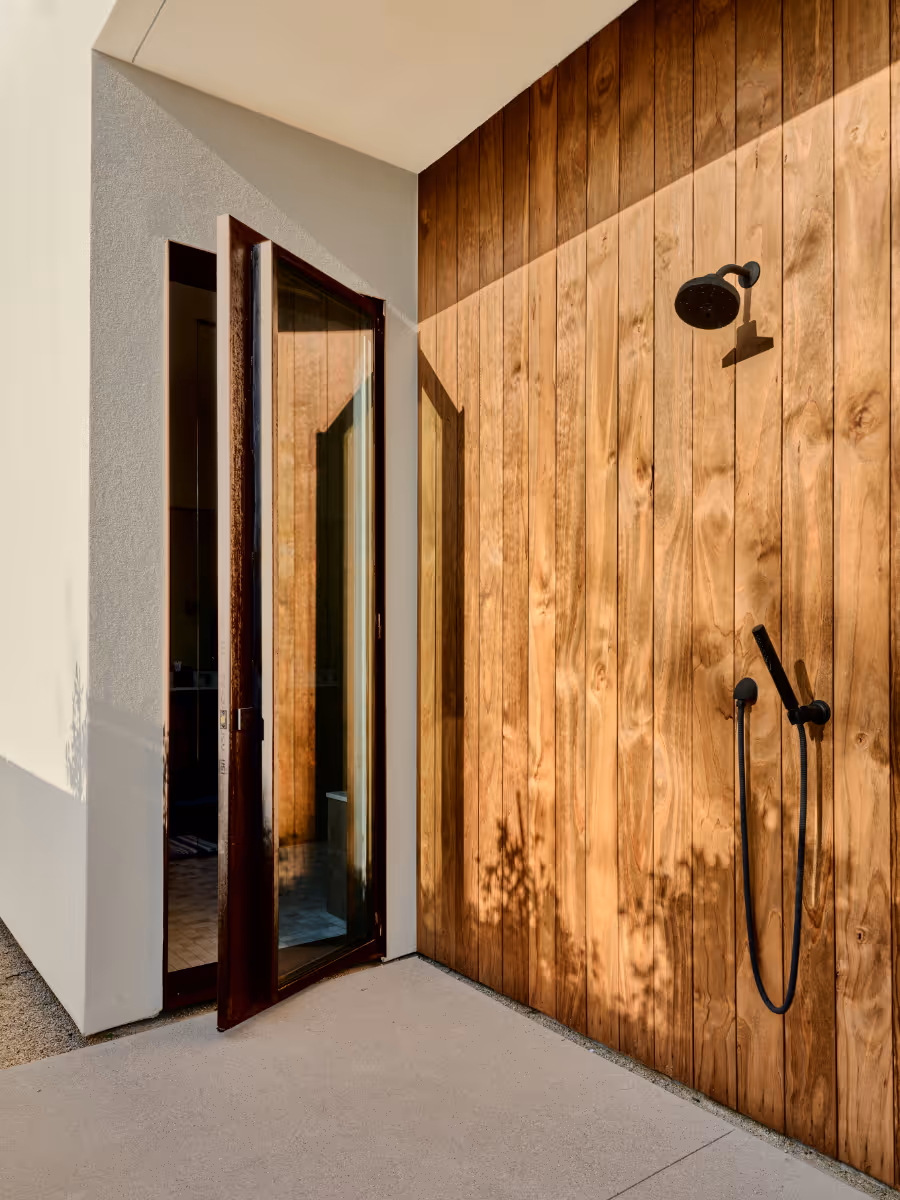 an outdoor shower with wood and stucco siding
