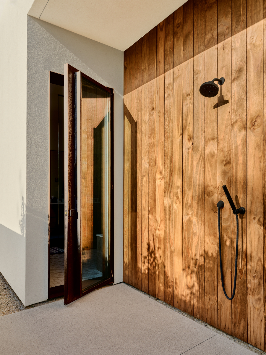 an outdoor shower with wood and stucco siding