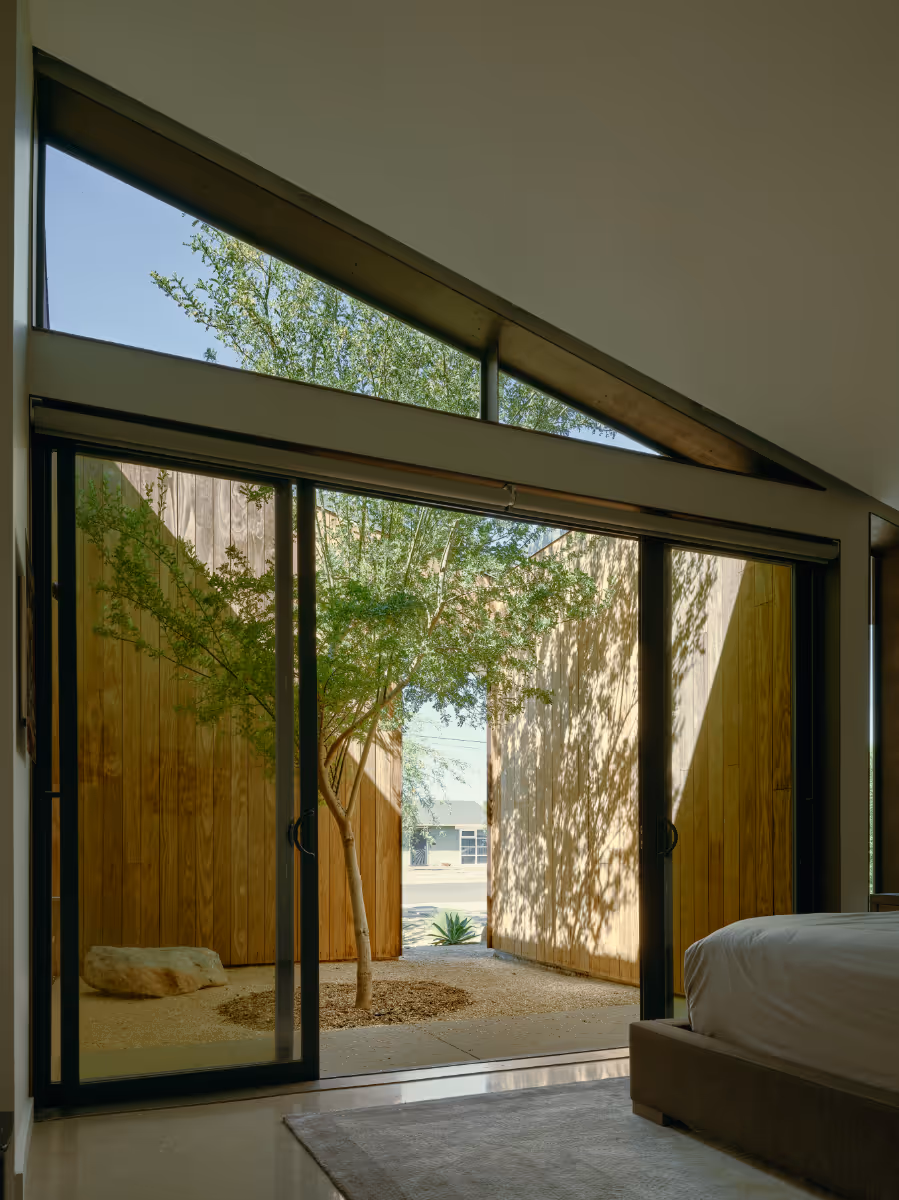a bedroom courtyard with wood siding and a tree