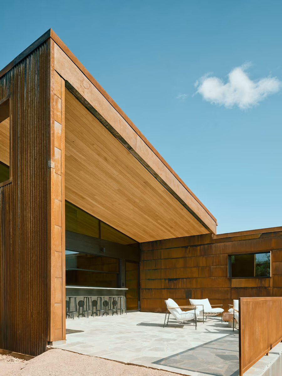 Covered patio with hemlock soffit, outdoor bar seating and white lounge chairs on flagstone