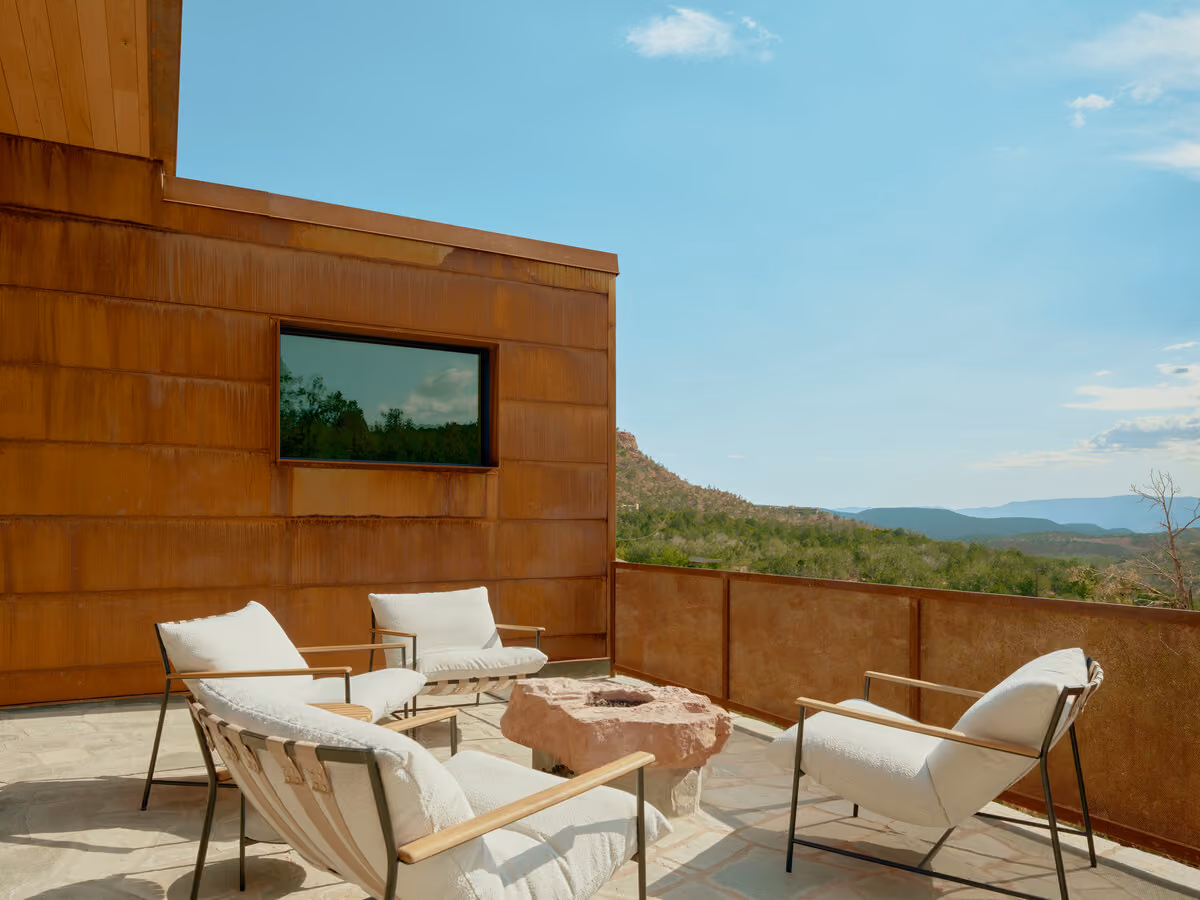 Flagstone terrace with four white lounge chairs around a red sandstone fire pit and canyon views