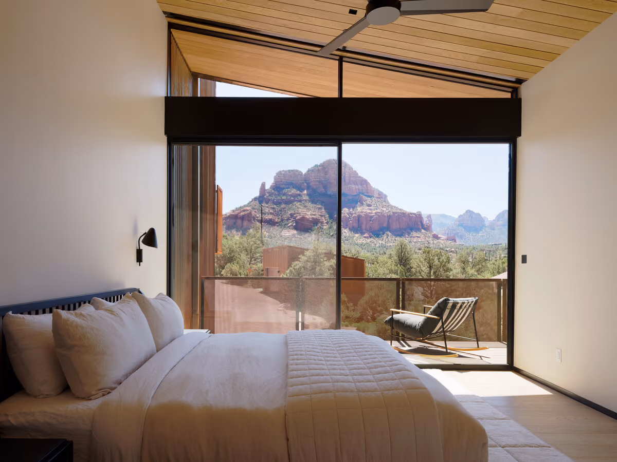 King bedroom with sliding glass opening onto a private deck and red rock views