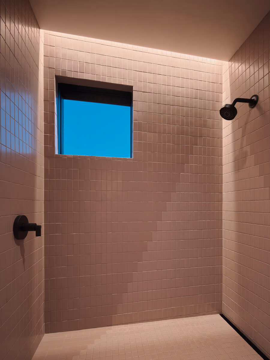 Blush pink tile shower with a square window cut to open sky