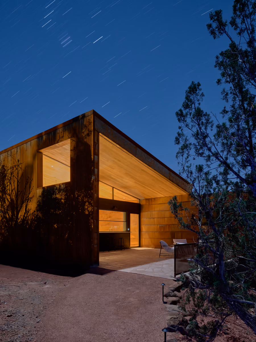 Fox under a star-trailed night sky, covered patio and bar lit from within