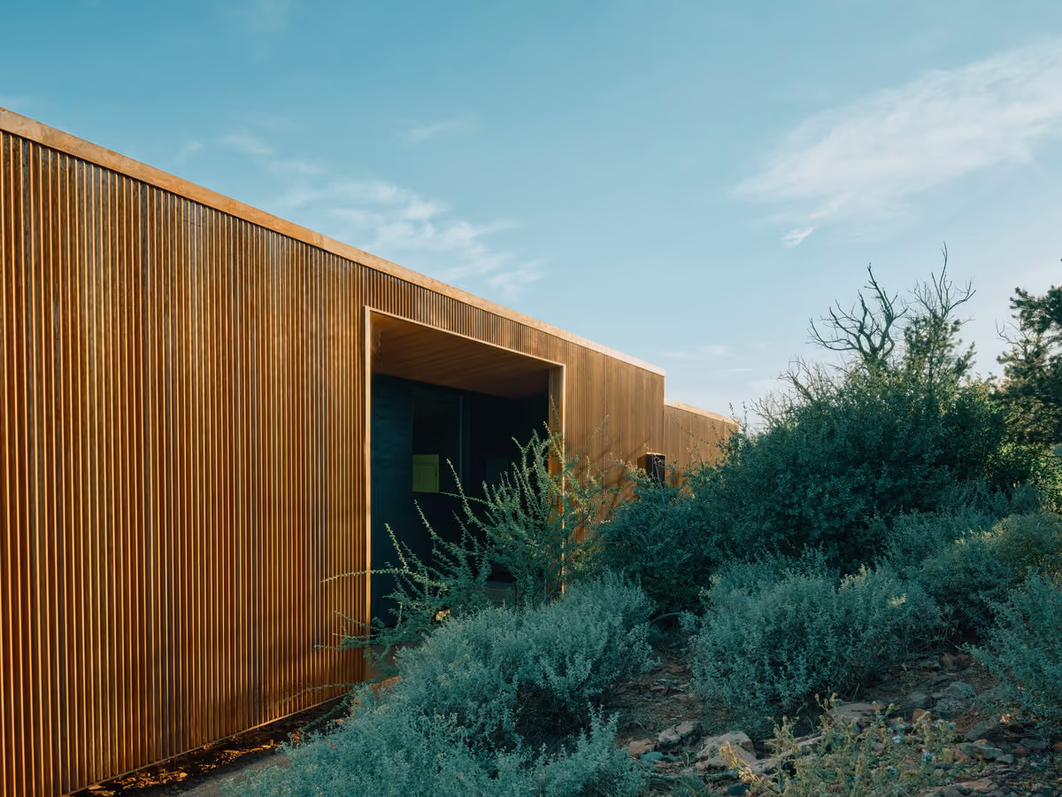 Corrugated weathering steel wall with a recessed opening, desert brush in the foreground