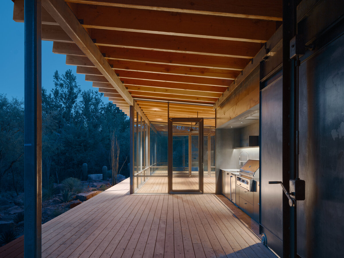 night view of kitchen and covered patio of modern pavilion in the woods by a creek in Sedona