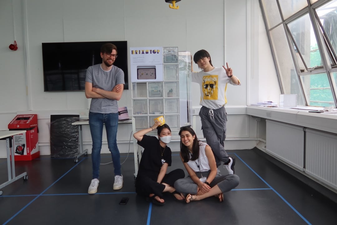 A group of people standing in front of a white tower called "Brixstop"
