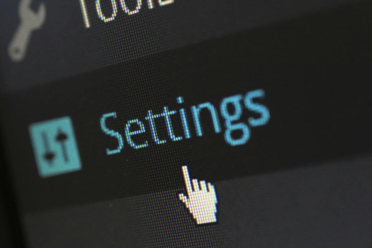 Close-up of a computer screen displaying the "Settings" menu option with a cursor pointing at it.