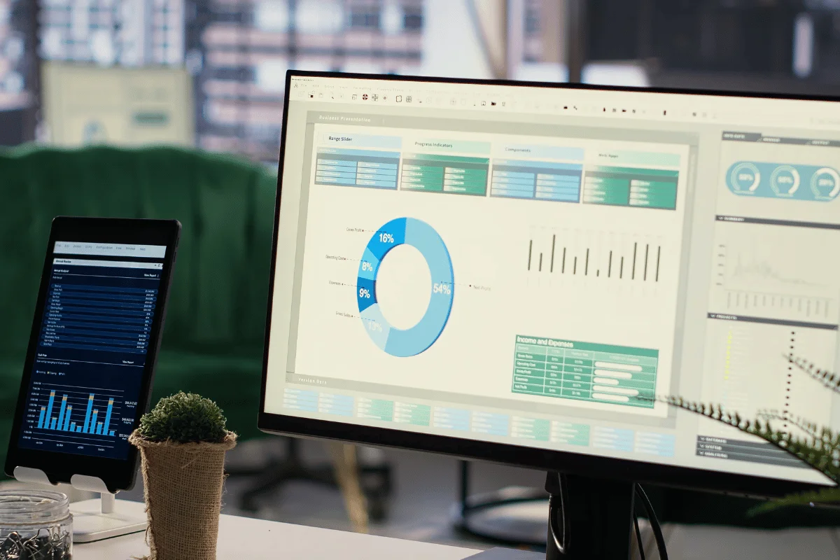 Dual monitors showing business analytics dashboards and performance charts on a modern office desk.