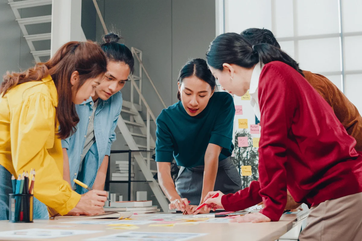 Creative team brainstorming ideas together around a table in a modern office workspace.