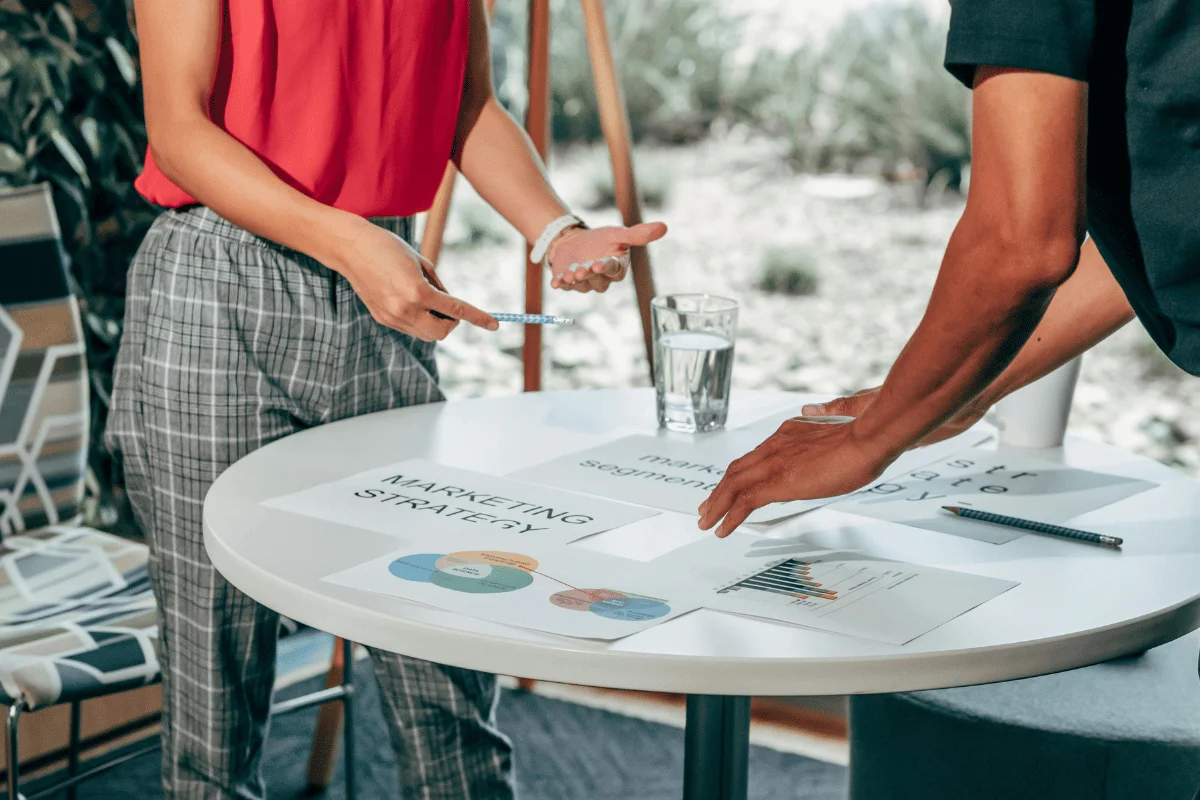 Team reviewing a marketing strategy document with charts and notes around a round meeting table.