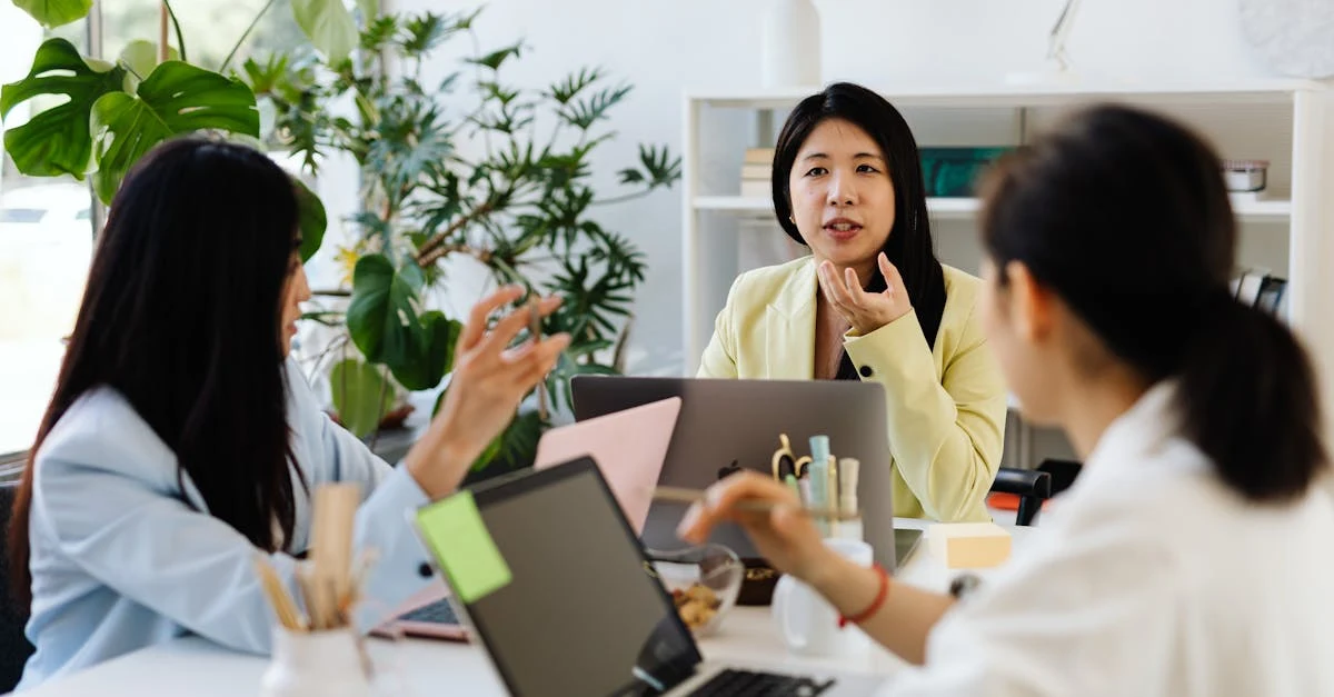 Three professionals collaborating at laptop discussing enterprise SEO patterns strategy in bright office with plants.