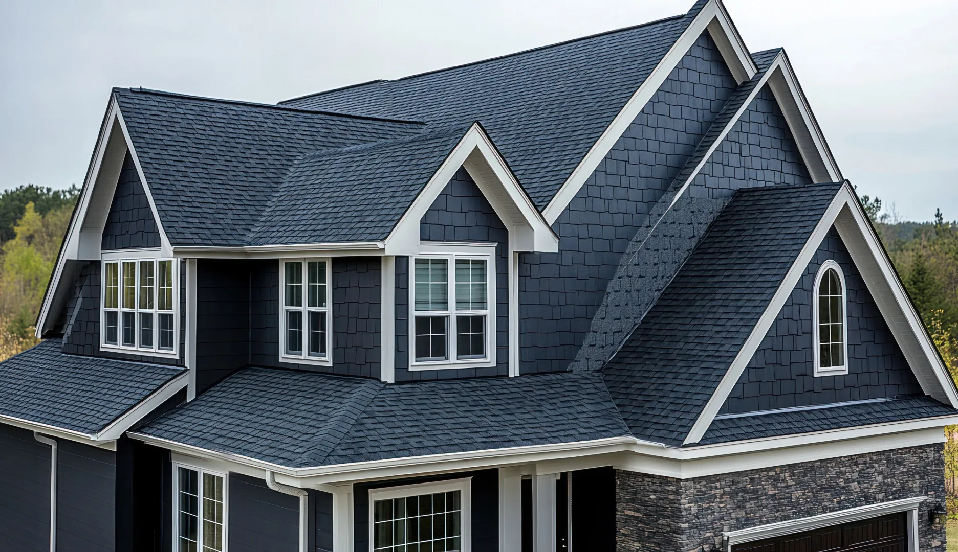 Modern two-story house with dark gray shingles, white trim, and a gabled roof design.