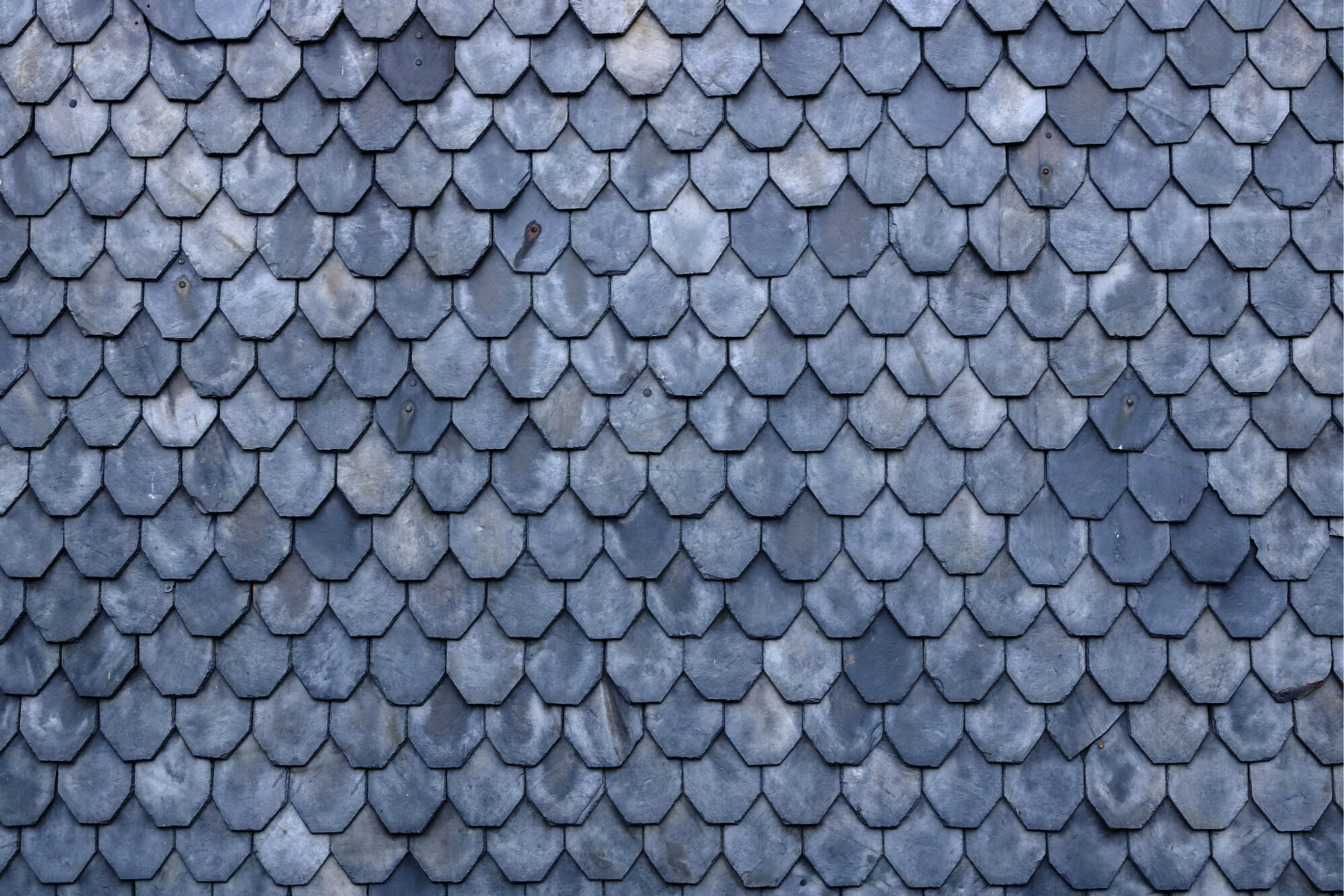 Close-up of a lmainated slate roof with overlapping gray shingles for architectural design inspiration.