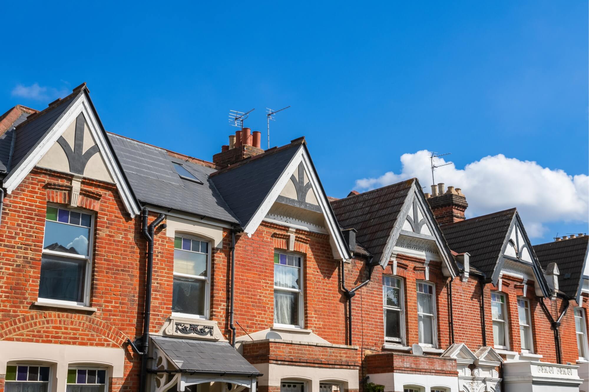 Row of traditional brick houses with gabled roofs under a clear blue sky.