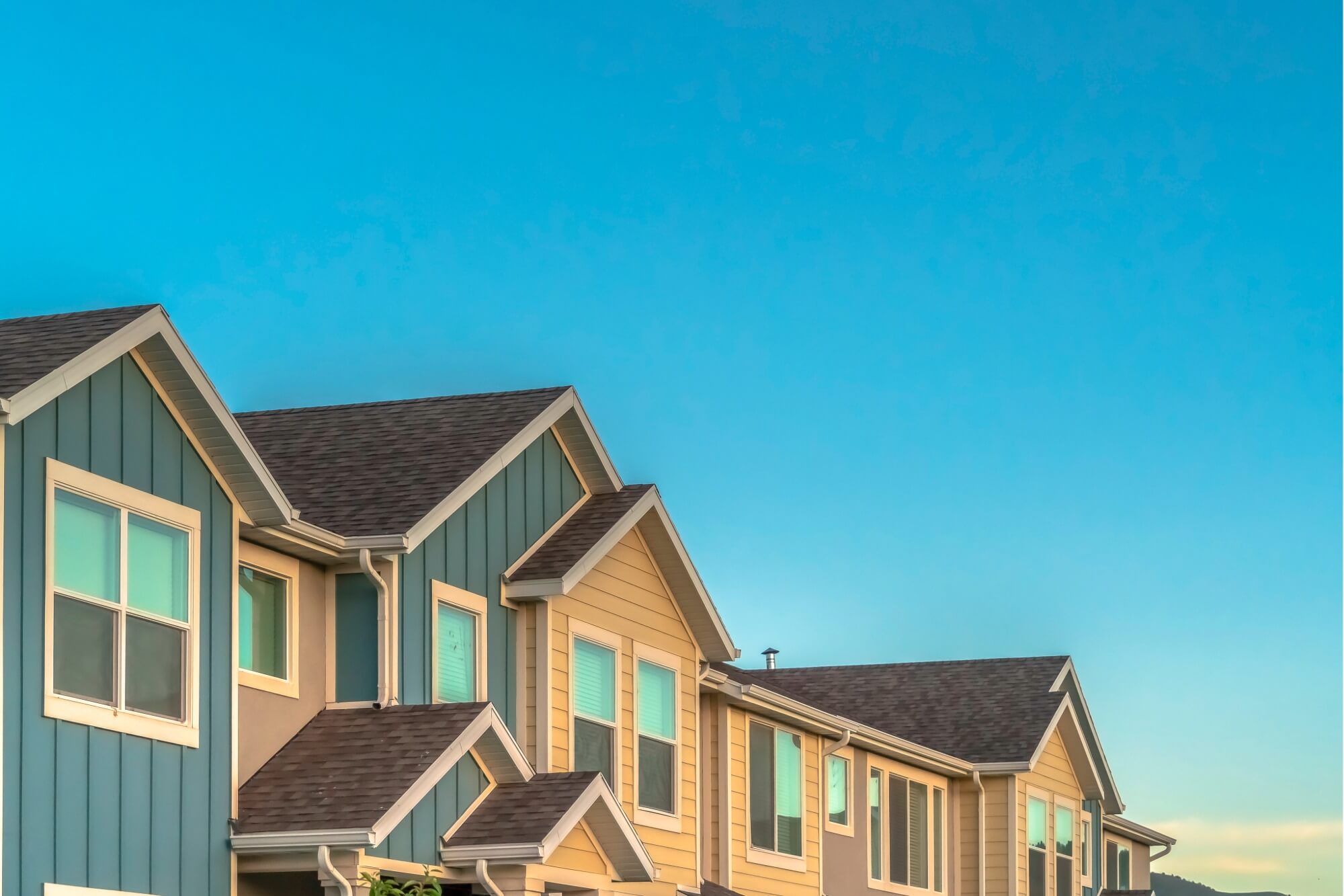 Row of modern suburban townhouses under clear blue sky.
